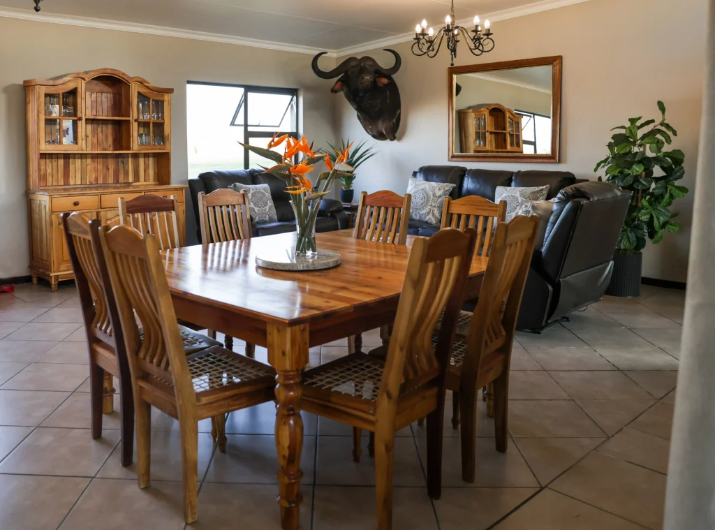 Stylish lounge area with vintage wooden chairs, circular woven rug, and nested wooden coffee tables under a large wall mirror.