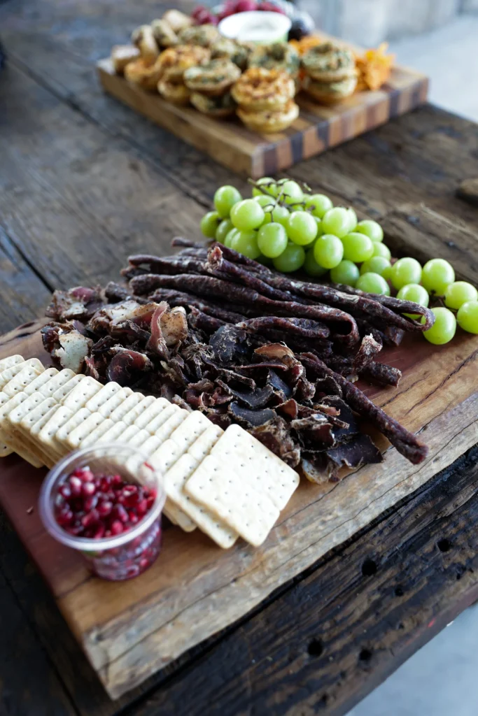 Gourmet charcuterie board featuring biltong, crackers, grapes, and pomegranate at a Free State hunting retreat.