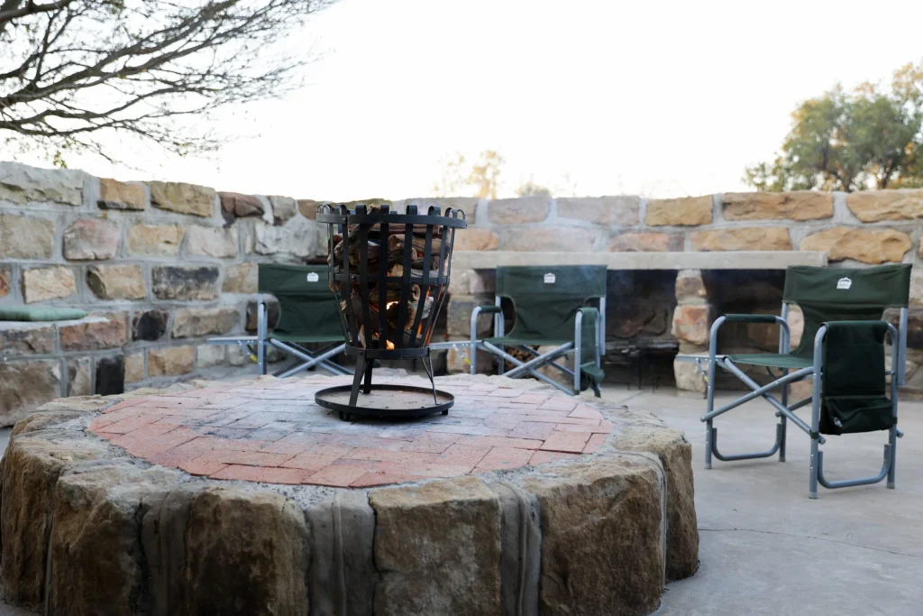 Inviting firepit area surrounded by canvas chairs at an exclusive hunting lodge in the Free State.