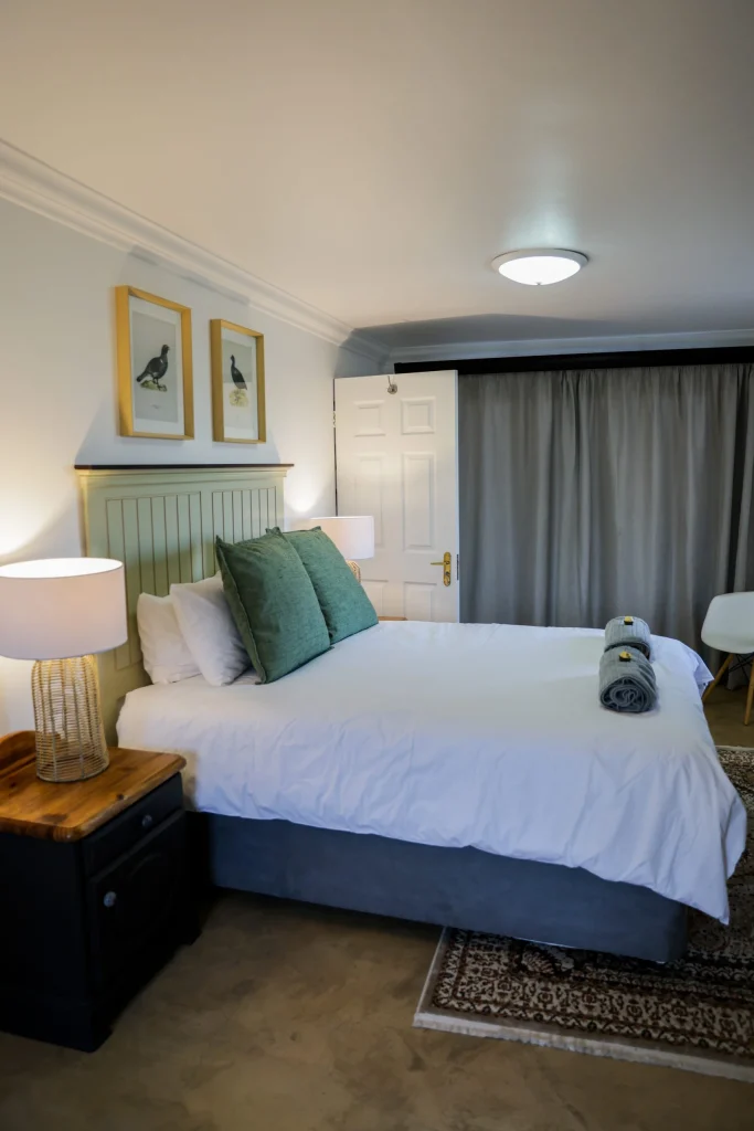 Cozy stone-walled bedroom with a green upholstered headboard, elegant bedside tables, and warm ambient lighting