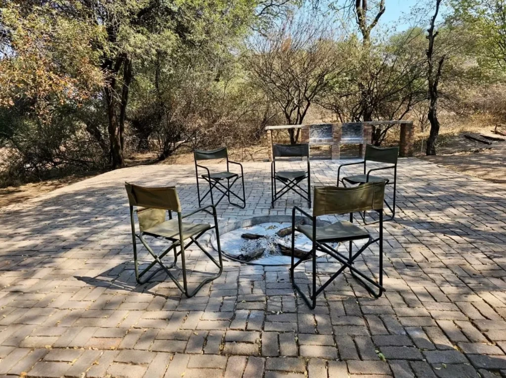 Campfire seating area with canvas chairs arranged around a firepit in a natural bushveld setting in Botswana.